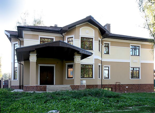 Оштукатуренный фасад дома в коттеджном посёлке Подмосковья. 