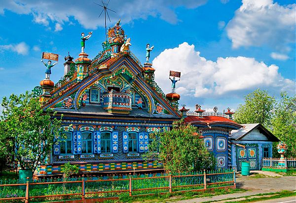 Архитектурное излишество в этом доме складывается из чересчур сложной формы фронтона с навершием и башенками, чрезмерного количества резьбы, окрашенной в разные цвета, скульптурным изображениям несвязанной между собой тематики. 