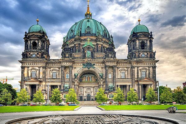 Центральный фасад Берлинского собора, украшенный росписью, бронзовыми скульптурами и массивным куполом, увенчанным позолоченным крестом.
