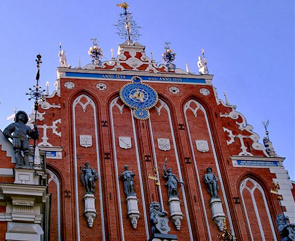 Четыре статуи на главном фасаде Дома Черноголовых, символизирующие единство торговли и стратегии, расположены в декоративных нишах, украшенных гербами и лепниной.