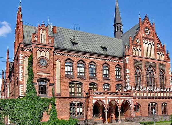 Центральный фасад Латвийской Академии Художеств дополнен традиционными для архитектуры неоготики элементами: массивным арочным входом, облицовкой рустованными панелями и декоративными шпилями.